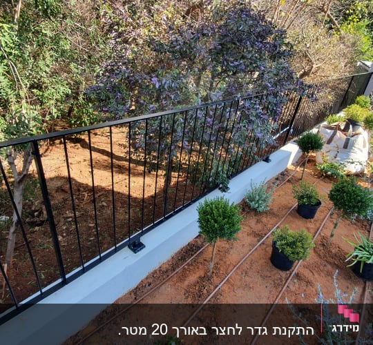 גדר מתכת שחורה עם צמחים מסודרים לאורך השביל